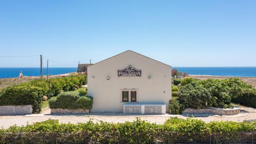 a white building with the ocean in the background at Palascìa Wellness Relais in Otranto