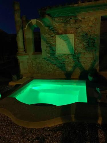 une piscine avec une lueur verte dans le noir dans l'établissement Maison élégante à Villalier avec Jacuzzi, à Laprade