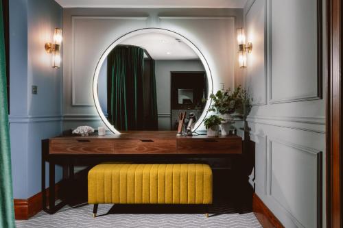 a bathroom with a yellow stool and a mirror at Kimpton Clocktower by IHG in Manchester