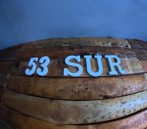 a sign on top of a wooden barrel at Hostel 53 Sur in Puerto Natales