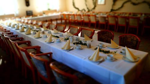 a long table in a room with red chairs at Landhotel Wilhelm Busch in Lüthorst