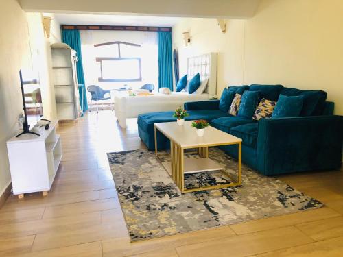 a living room with a blue couch and a table at Harmony Homes Beachfront in Diani Beach