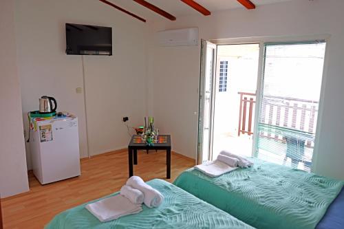 ein Zimmer mit zwei Betten und einem Kühlschrank und einem Fenster in der Unterkunft Rooftop rooms Ohrid in Ohrid