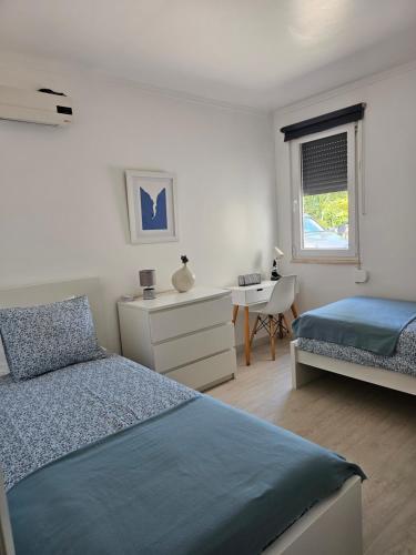 a bedroom with two beds and a desk and a window at Casa do Cedro no Campo in Correias