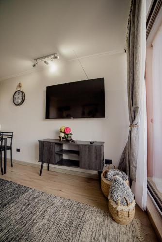 a living room with a flat screen tv on a wall at Departamento con terraza y vista al volcan in Pucón