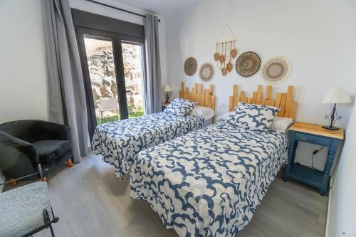 ein Schlafzimmer mit zwei Betten und einem Stuhl in der Unterkunft Villa Eden in El Gastor