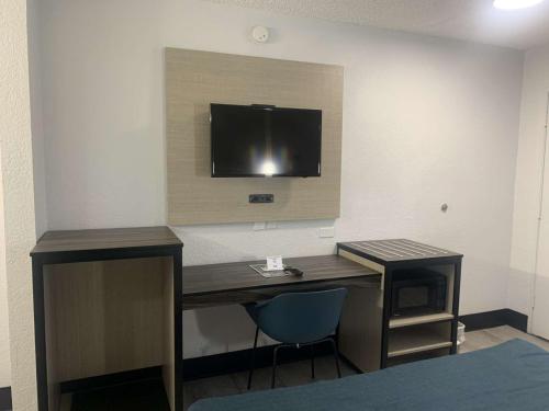 a room with a desk with a tv on the wall at Motel 6-Tempe, AZ - Broadway - ASU in Tempe