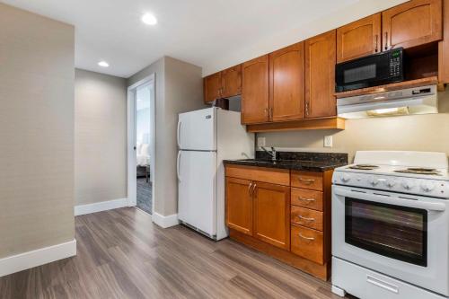 a kitchen with wooden cabinets and a white refrigerator at Best Western Plus Kelowna Hotel & Suites in Kelowna