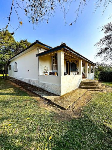 a small white house with a grass yard at Fazenda com fácil acesso - Piscina e churrasqueira in Biritiba-Mirim