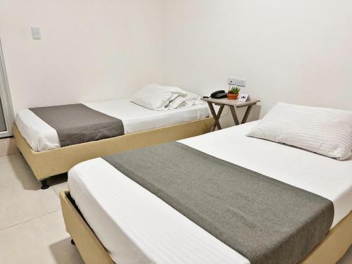 two beds in a room with a table at Hotel Boutique Gao in Cúcuta