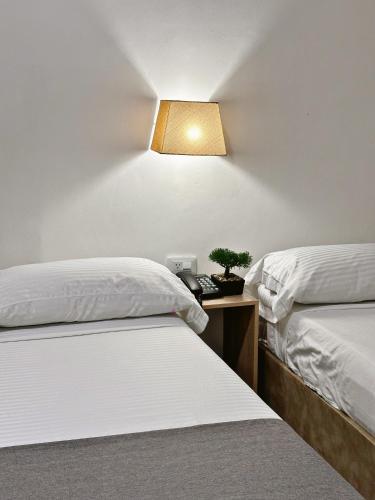 a room with two beds and a light on the wall at Hotel Boutique Gao in Cúcuta