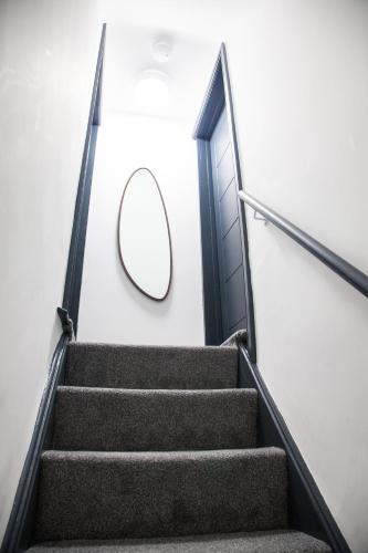 a circular mirror on a wall next to a stairway at Stylish Home, hosted by ESONGRACE Stays, Stoke-on-Trent - Perfect for Families - Contractors - Holiday makers - Emergency Housing - Professionals, Relocators in Stoke on Trent
