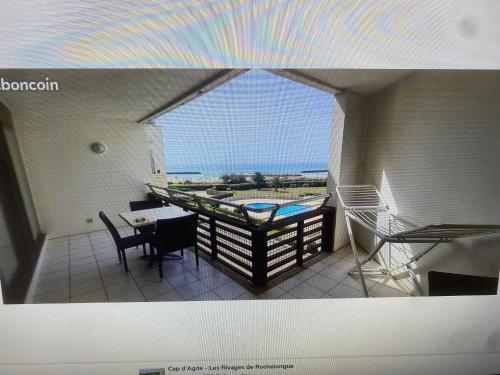 un balcon avec une table, des chaises et un arc-en-ciel dans l'établissement Cap d Agde Rochelongues, au Cap d'Agde