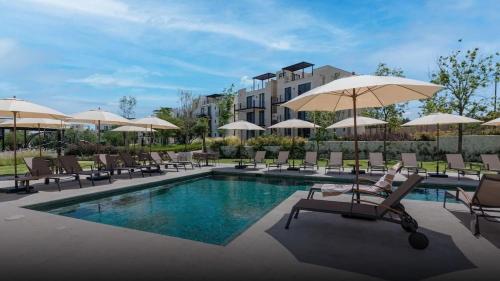 a pool with chairs and umbrellas next to a building at Deluxe Design Condo, San Miguel in San Miguel de Allende