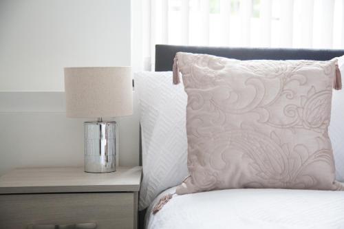 a bedroom with a bed with a pillow and a lamp at Stylish Home, hosted by ESONGRACE Stays, Stoke-on-Trent - Perfect for Families - Contractors - Holiday makers - Emergency Housing - Professionals, Relocators in Stoke on Trent