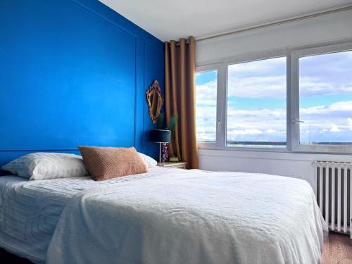 - une chambre bleue avec un lit et une grande fenêtre dans l'établissement Luxe Évasion avec vue incroyable, parking gratuit, à Maisons-Alfort