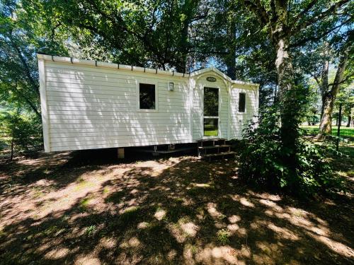 une maison blanche assise à l'ombre d'un arbre dans l'établissement Mobil Home Titania, à Villemur-sur-Tarn
