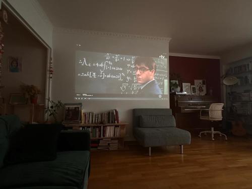 un écran de projection dans un salon avec un homme dessus dans l'établissement Appartement comfortable 19e, à Paris