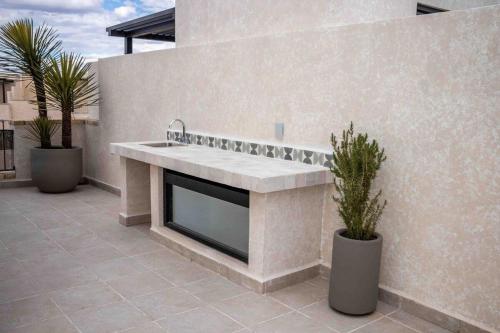 a stone fireplace on a patio with two potted plants at CASA preciosa en SAN MIGUEL con alberca, 6PAX 4bed in San Miguel de Allende