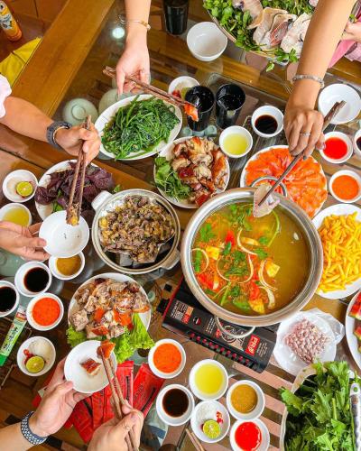 a table full of food with people holding chop sticks at Ngọc Anh Guest House in Sa Pa