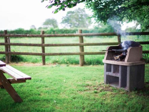 a cat is sitting on a grill in a yard at Maison de campagne familiale aux Alpes mancelles - 3 chambres, cheminée et activités proches - FR-1-410-149 in Saint-Léonard-des-Bois