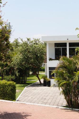 a white building with a walkway in front of it at Rancho Macloy Hotel Spa & Social Events in Yautepec