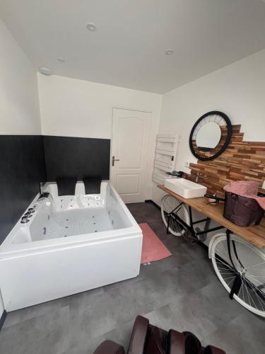 a large white bath tub in a room with a table at Évasion centre ville Avranches proche du mont saint Michel in Avranches
