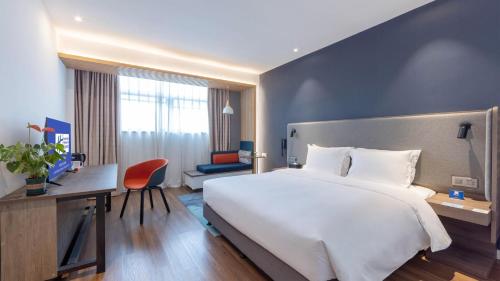 a hotel room with a large white bed and a desk at Holiday Inn Express Chengdu Wuhou New City by IHG in Chengdu