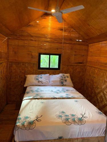 a bed in a small room with a ceiling fan at Rose Guest House in Canhangdon