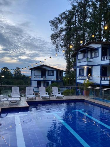 a pool with chairs and a house in the background at Hotel Campestre el Volcan De Guatape in Guatapé