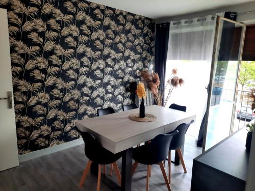 a dining room table with black and white wallpaper at La Cornée Renard in Saint-Dizier