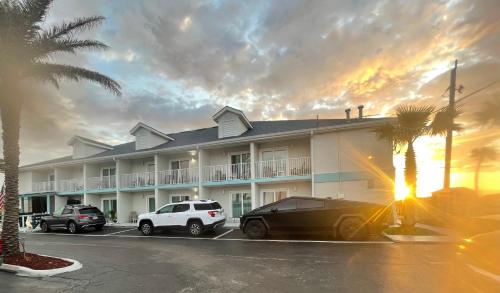 a large building with cars parked in a parking lot at Ocean Sands Beach Boutique Inn-1 Acre Private Beach-St Augustine Historic-2 Miles-Shuttle with Downtown Tour-HEATED Salt Water Pool until 420AM-Popcorn-Cookies-New 4k USD Black Beds- 69 Item Breakfast-Eggs-Bacon-Starbucks- Free Laundry- #904-799-SAND in Saint Augustine