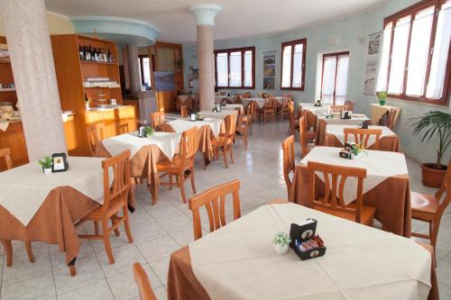 a restaurant with white tables and wooden chairs at Hotel Jasmine in Teulada