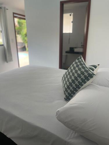 a white bed with a pillow on top of it at Do Adriano Suites in Búzios
