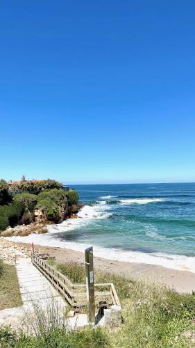a beach with a wooden staircase leading to the ocean at The Cliffs A Ribeira - Llas in Foz