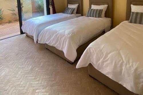 a bedroom with two beds with white sheets and a window at Luxueuse villa Proche Agadir et Taroudant pour 6 pers Piscine Privée sans vis à vis in Agadir