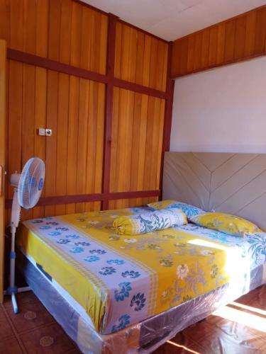 a bedroom with a bed with a fan and wooden walls at Bunaken GuestHouse in Bunaken