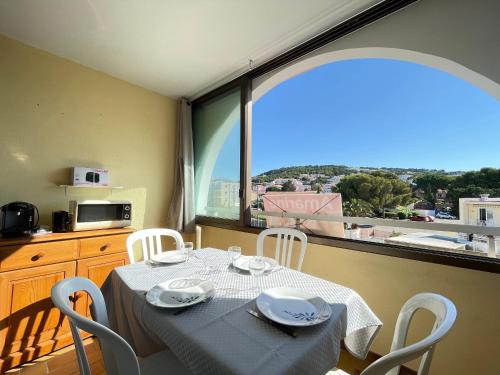 une table de salle à manger avec des chaises et une grande fenêtre dans l'établissement Studio cabine cosy, proche plage, parking privé, animaux admis - FR-1-338-559, à Sète
