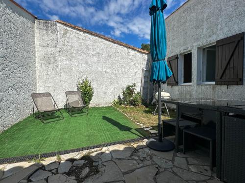 un patio avec deux chaises, une table et un parasol dans l'établissement Maison de vacances rénovée à La Palmyre - 2 chambres, proche mer et commerces, patio privé. - FR-1-705-72, aux Mathes