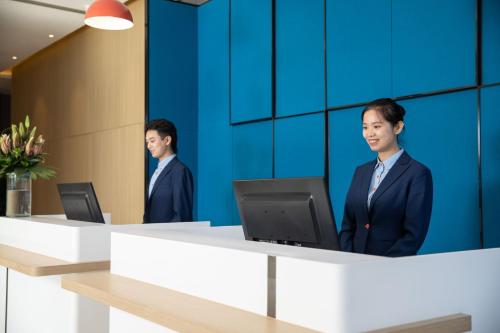 two men in suits standing at a desk with a computer at Holiday Inn Express Chengdu Wuhou New City by IHG in Chengdu