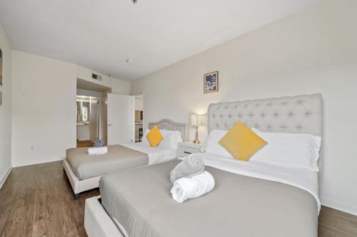 2 camas en una habitación con almohadas blancas y amarillas en Le Reve , 5 min to the beach Luxury Condo, en Los Ángeles