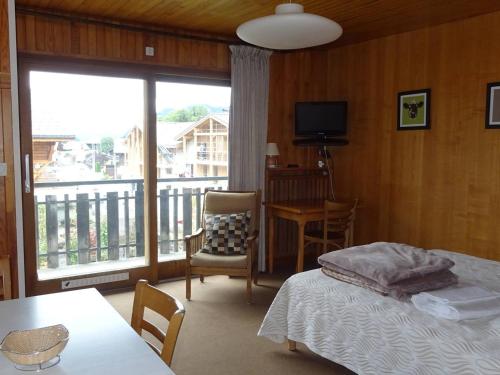 - une chambre avec un lit et un balcon avec une télévision dans l'établissement Studio cosy aux Gets - Centre-ville, proche commodités, Wifi, draps et serviettes inclus - FR-1-802-30, aux Gets
