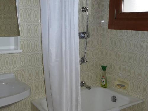 La salle de bains est pourvue d'un rideau de douche blanc et d'un lavabo. dans l'établissement Studio cosy aux Gets - Centre-ville, proche commodités, Wifi, draps et serviettes inclus - FR-1-802-30, aux Gets