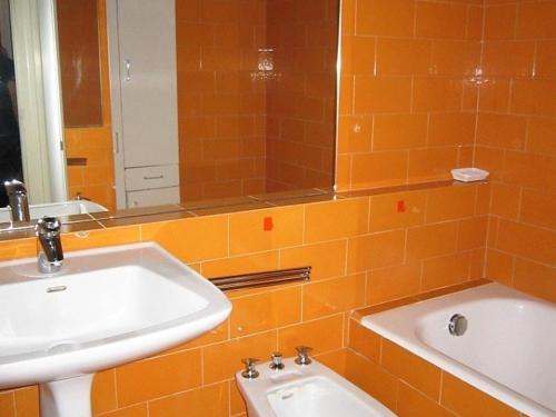 La salle de bains est pourvue de carrelage orange, d'un lavabo et d'un miroir. dans l'établissement Les Gets - 2 pièces, 4 pers, centre station, garage, à 100m des commerces et de l'ESF - FR-1-802-13, aux Gets