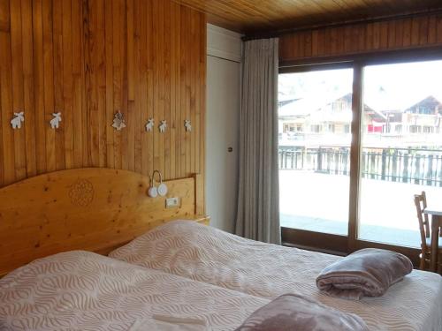 une chambre avec un lit et une grande fenêtre dans l'établissement Spacieux 3 pièces central aux Gets - 6 pers, garage, WiFi, draps et serviettes inclus - FR-1-802-25, aux Gets