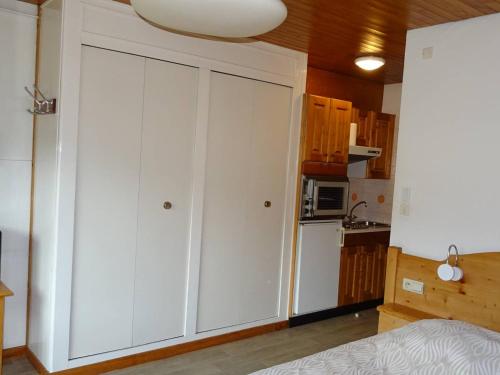 une cuisine avec des armoires blanches et un réfrigérateur blanc dans l'établissement Studio au cœur des Gets - 2 Pers - WIFI, Draps et Serviettes Inclus, Près des Commerces - FR-1-802-43, aux Gets