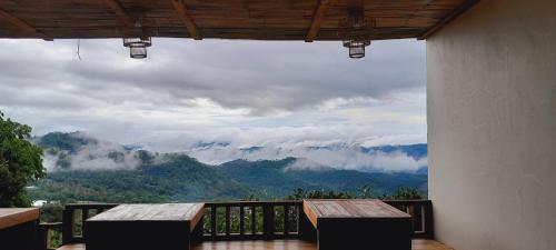 a balcony with a table and a view of mountains at KHIRI HOUSE &Café Farm ดอยช้างเชียงรายที่พักอาข่าเรียวกังสไตล์กลางหมู่บ้านดอยช้าง in Ban Rong Than