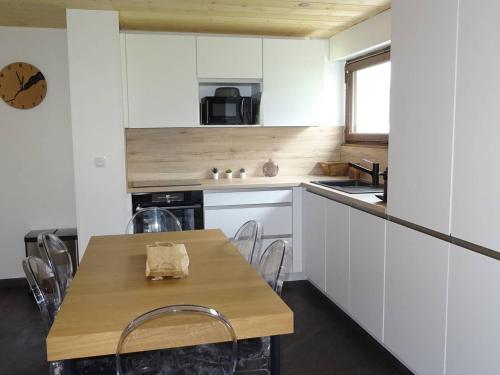 une cuisine avec des armoires blanches et une table en bois dans l'établissement Les Gets - Spacieux 2 Pièces Rénové, 4-6 Pers, Parking, Centre-Ville, Proche Commerces et Ski - FR-1-802-51, aux Gets