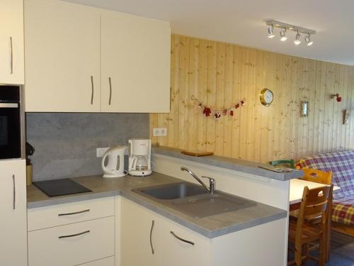 une cuisine avec des armoires blanches et un évier dans l'établissement Appartement 2 pièces + coin cabine, Les Gets, 5 pers, confort, proche centre, garage - FR-1-802-65, aux Gets
