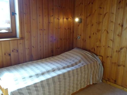 - une petite chambre avec un lit dans un mur en bois dans l'établissement T2 confort 4 pers, Wi-Fi, garage, 150m commerces, 100m télécabines - FR-1-802-74, aux Gets